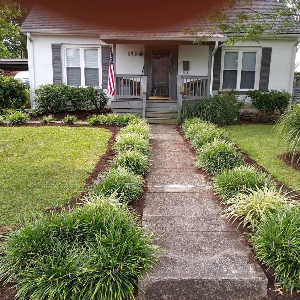 Manicured front walkway lined with liriope grass borders leading to porch